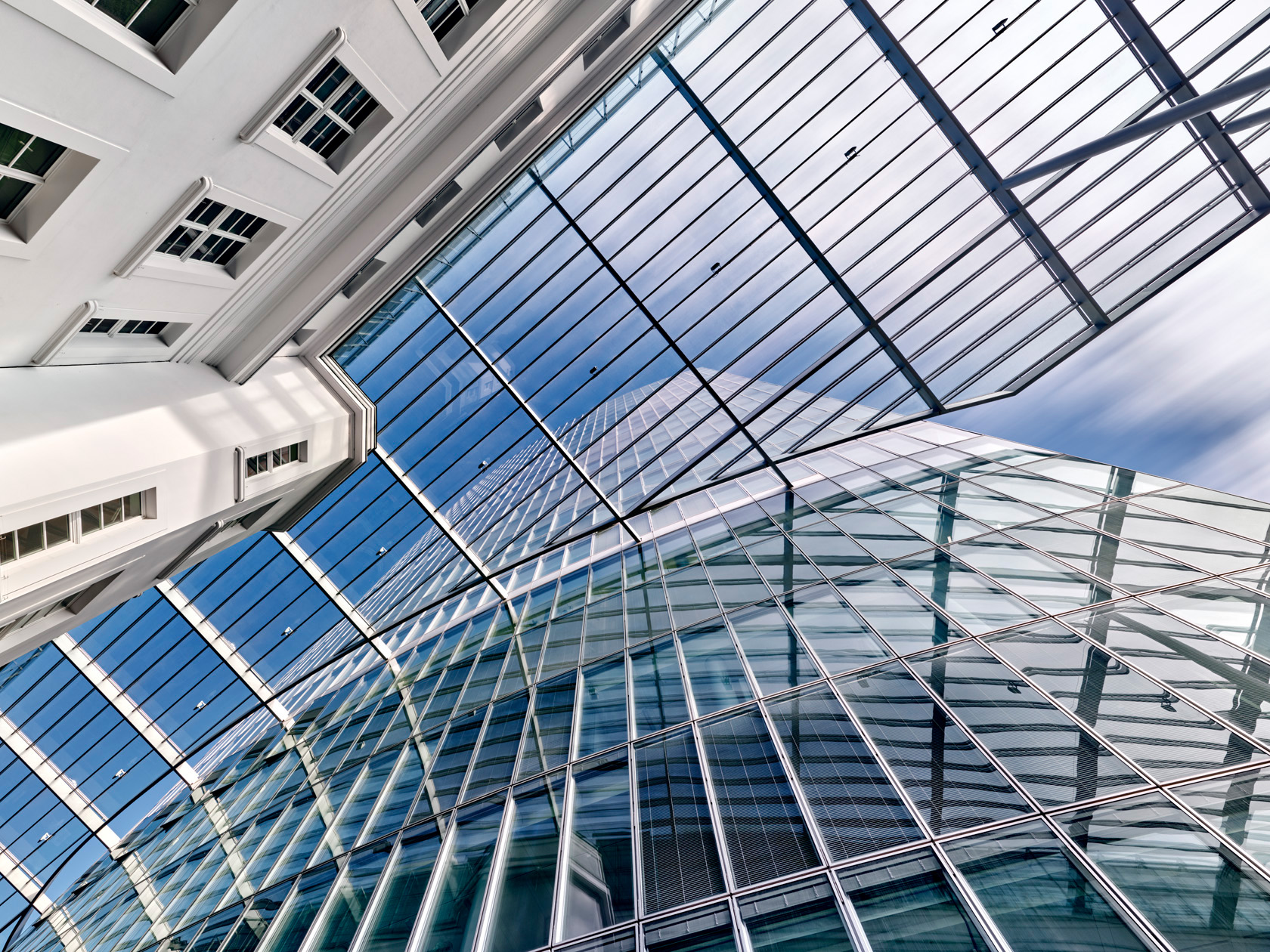 Der Fotograf Herbert Böttcher zeigt eine Aufsicht zwischen einem weißen Altbau und dem modernen Glasgebäude GAP 15 mit Wolkenreflexionen.