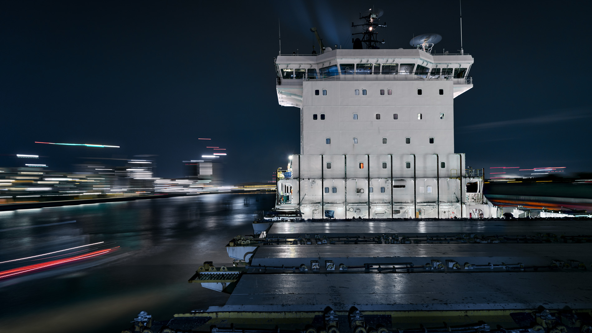 Blick Richtung weißem Aufbau über das angeleuchtete unbeladene Deck des Containerschiffs Elbsun während nächtlicher Fahrt auf der Elbe bei Hamburg. In seinem Langzeitprojekt Seamotion präsentiert der Fotograf Herbert Böttcher künstlerische Fotografien von Frachtschiffen auf den Weltmeeren.