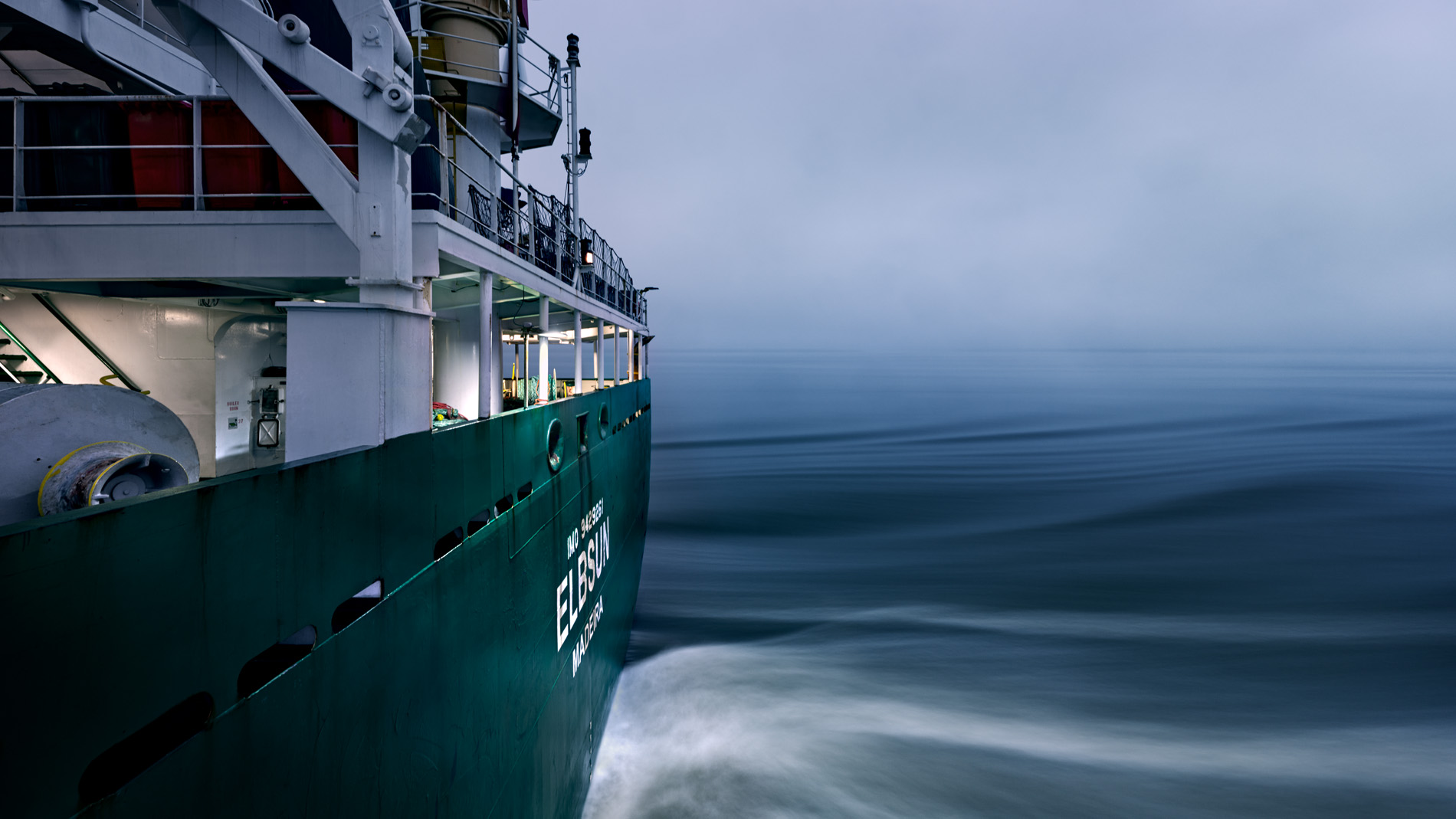 Das Heck des Containerschiffs Elbsun während der Fahrt in der Dämmerung. In seinem Langzeitprojekt Seamotion präsentiert der Fotograf Herbert Böttcher künstlerische Fotografien von Frachtschiffen auf den Weltmeeren. Die Bildreihe MS Elbsun entstand in Kooperation mit der Elbdeich Reederei, Drochtersen.