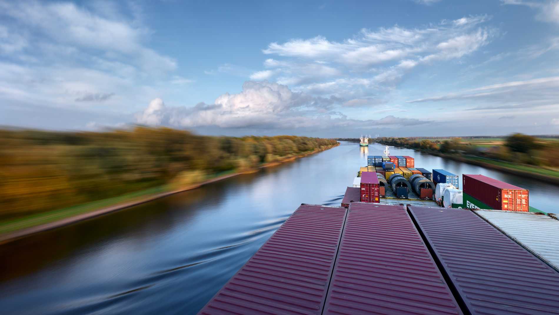 Blick vom Aufbau über dass Vorschiff des Containerschiffs Elbsun während der Fahrt auf dem Nordostseekanal in der Abenddämmerung. In seinem Langzeitprojekt Seamotion präsentiert der Fotograf Herbert Böttcher künstlerische Fotografien von Frachtschiffen auf den Weltmeeren. Die Bildreihe MS Elbsun entstand in Kooperation mit der Elbdeich Reederei, Drochtersen.